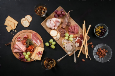 a-table-set-with-european-style-drinks-and-snacks-on-a-black-wooden-table